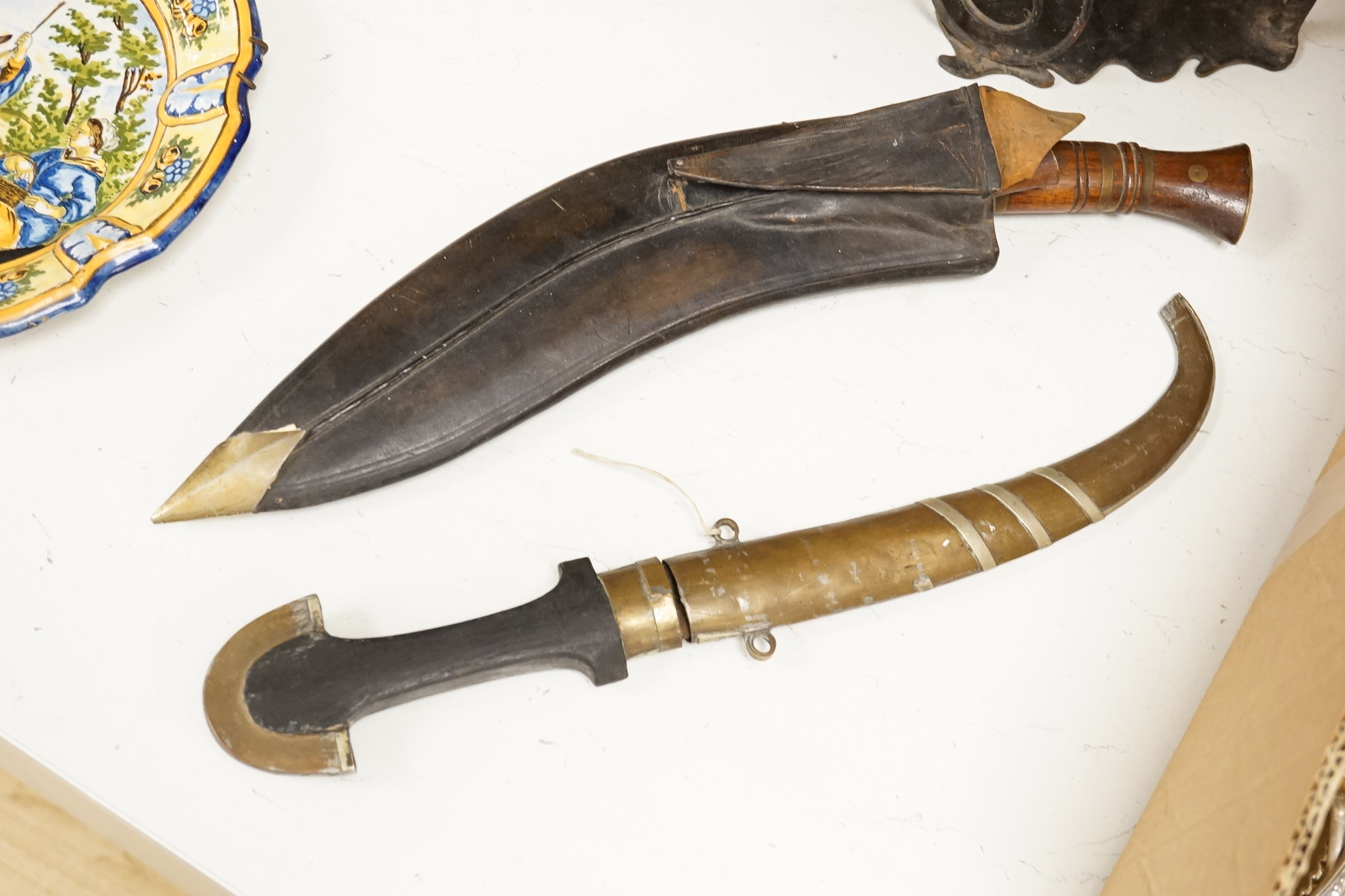 An Indian Kukri with brass mounted wooden handle its leather sheath, and a Moroccan Jambiya, together with a hardstone and wrought iron candle stand